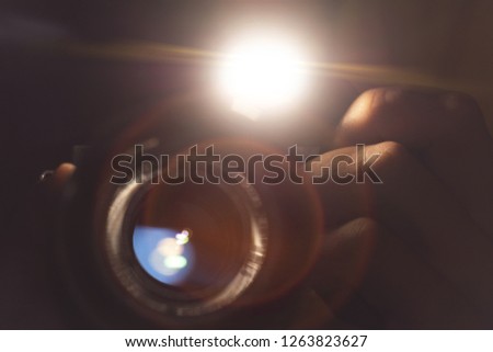 The photographer is holding a camera. Photographs with flash. Close-up