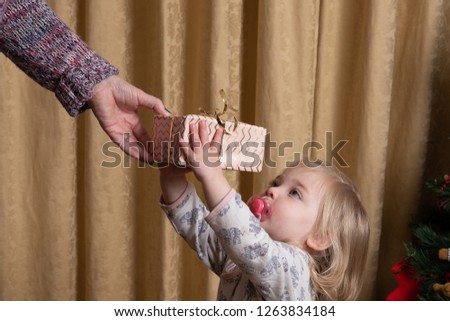 Eighteen month old Caucasian  infant accepting a Christmas gift. 