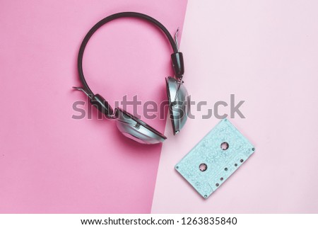 Wireless headphones and audio cassettes on a multicolored pastel paper background. Minimal creative art. Musical retro vibrations. Top view.