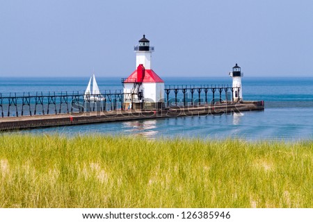 St. Joseph, Michigan North Pier Lighthouses with a Sailboat on Lake Michigan. Royalty-Free Stock Photo #126385946