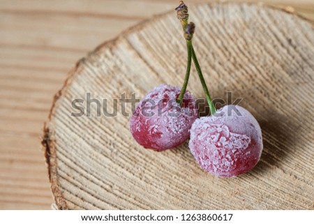 Two frozen cherries on a wooden background