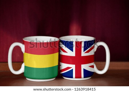 United Kingdom and Bolivia flag on two cups with blurry background