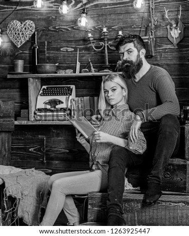 Couple in love reading poetry in warm atmosphere. Romantic evening concept. Couple in wooden vintage interior enjoy poetry. Lady and man with beard on dreamy faces with book, reading romantic poetry.