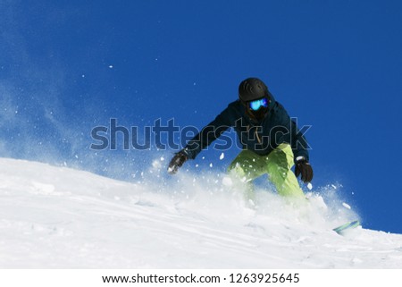 Bright extreme photo of young sportive snowboarder in sunny winter day
