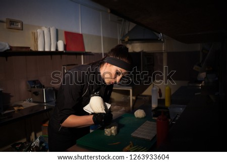 woman prepares delicious sushi in the kitchen at restaurant