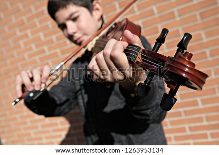 teenager playing violin with shallow depth of field.  Focus on the hand in the foreground