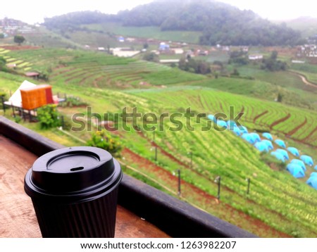 A cup of coffee is placed on the balcony.
The back is a mountain view, vegetable garden and patio tents