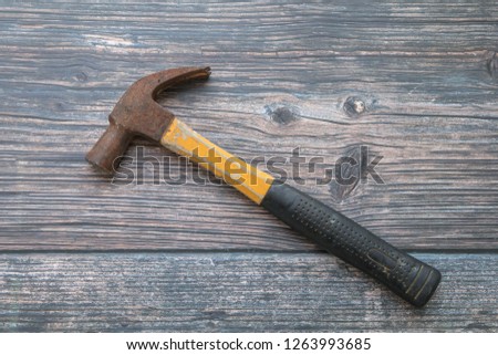 Old rusted yellow hammer on wooden background.