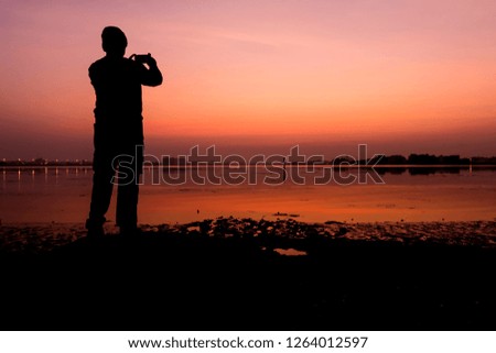 Silhouette of a tourist  at the beach taking picture in early morning of sunrise 
