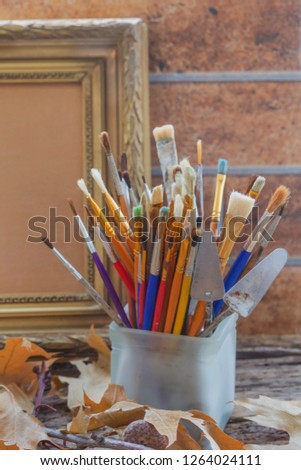 Art brushes in a glass on the background of the frame for painting