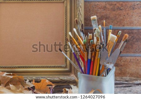 Art brushes in a glass on the background of the frame for painting