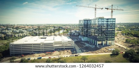 Panorama aerial view working crane at construction site of new corporate building high-rise and multistory garage parking