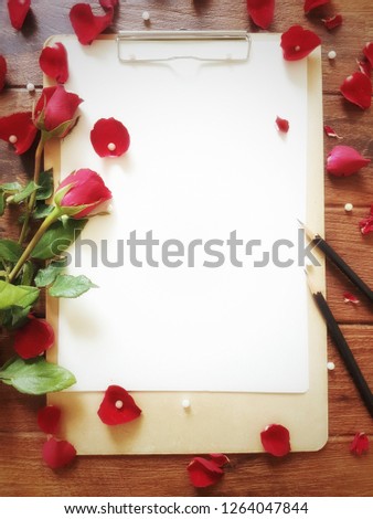 Paper, art board, pencil, red rose and pearl on wood table background for decoration on Valentine's day and wedding event.