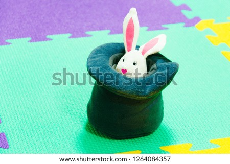 Toy christmas bunny looks out of hat. Magic rabbit. Close up, Horizontal banner, colorful background with copy space