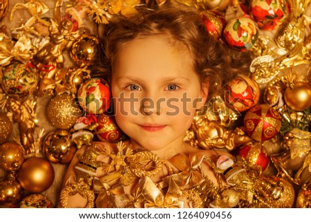 Little girl lying in a pile of tinsel and garlands