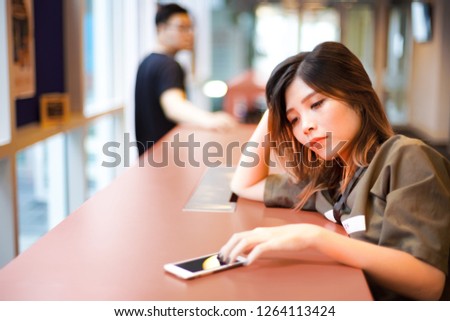 Lonely sad girl waiting for text message from smartphone on the table | Couple separated from each other