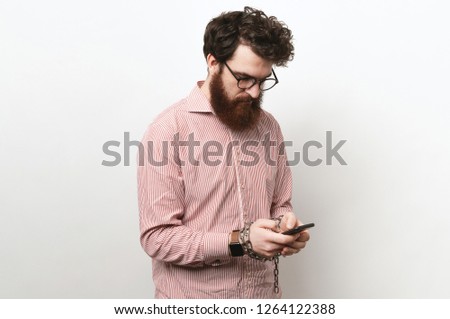 Bearded man in casual using smartphone with hands in chains