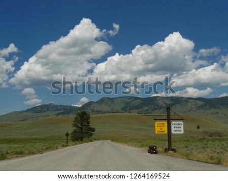 Roadside sign at Cooke Pass and caution on wildlife on roadway at Yellowstone National Park.