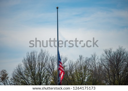 American (USA) flag to half-staff on a vertical pole on sky background. 
