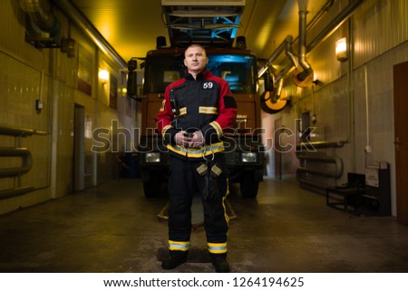 Full-length photo of firefighter on background of fire truck