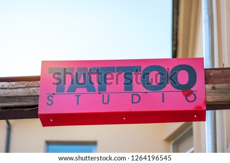 TATTOO STUDIO sign in black letters on a red background in the city