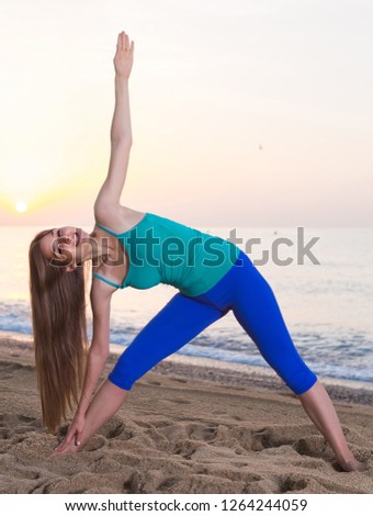 Portrait of sportswoman which is doing excercises on endurance on the beach near sea.
