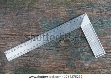 gray metal square tool lies on a wooden board