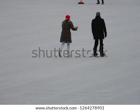 Man and woman with Santa cap skating at an outdoor ice rink