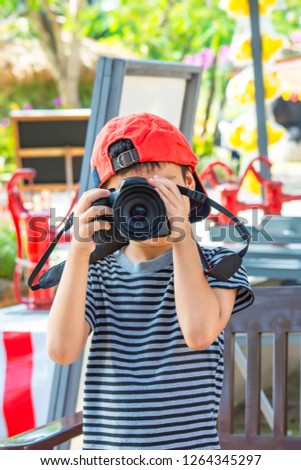Hand boy holding the camera Taking pictures in park.
