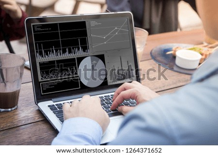 Businessman using laptop with stock chart statistics data on screen at meeting. 
