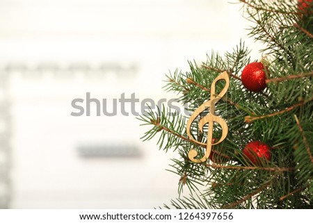 Fir tree with wooden treble clef against blurred background with space for text. Christmas music