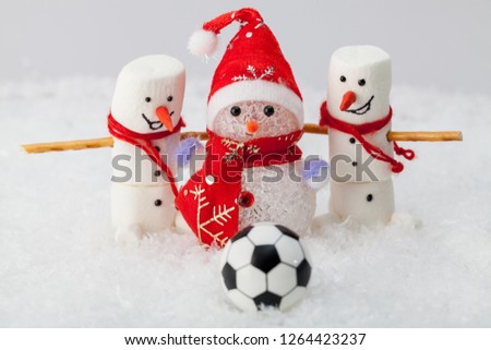 Three snowmen on white snow and a soccer ball in the foreground
