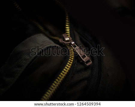 Beautiful and diverse subject. Black bag and backpack with a closure zipper and a buckle with a tag on a dark background.