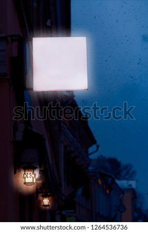 Winter street of a European city covered with snow with a blank sign on the wall of a building