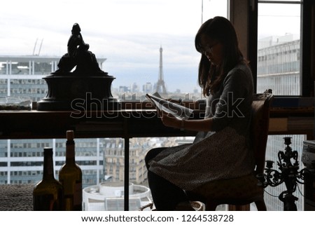 Woman sitting in French style room in Paris, background the Eiffel tower, France