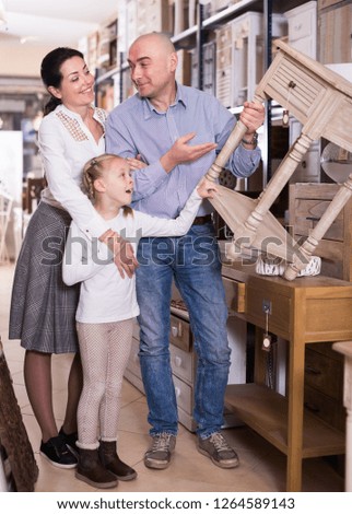 Happy family is choosing new nightstand for bedroom in the furniture store.