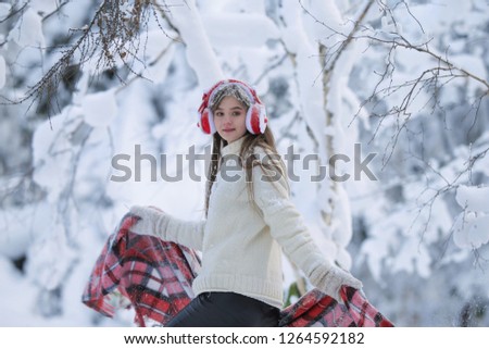 A young girl walks in the winter forest with a basket of mandarin.