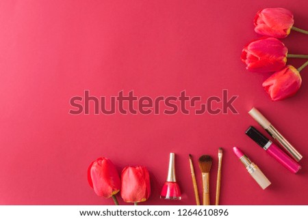 Flat lay composition with cosmetics and red tulip flowers on red table