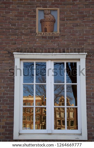 Amsterdam city refections in the glass window-frame of canal buildings. (translation uylenburch = owls castle or nest)
