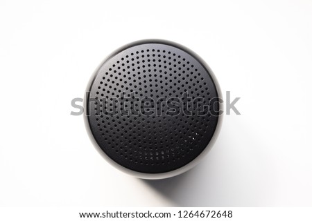 Black Wireless Bluetooth Speaker Isolated on Plain White Background, Viewed From Above;
Top View Showing Perforated Metal Grille Holes. Royalty-Free Stock Photo #1264672648