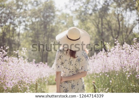 Girl with her back and  straw hat  in a field of flowers,Happy asian woman enjoying in  flower field, Enjoying Nature.