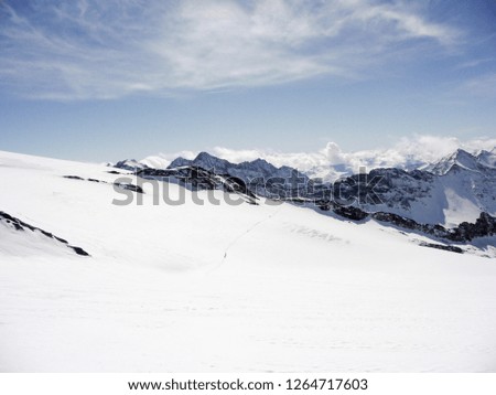winter moutnain landscape in the Austrian Alps with many backcountry skiers crossing a large glacier and a great background view