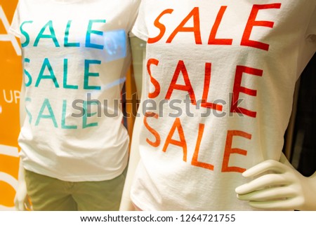 season sale slogan t-shirt on two mannequins in window in shopping mall, red and green color