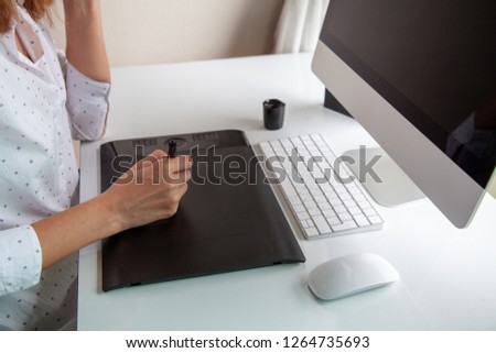 girl at a computer draws on a graphics tablet