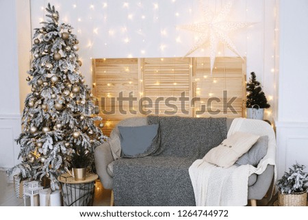 Christmas interior with white and blue color of a bright stylish living room with gifts, fireplace, Christmas tree and candles
