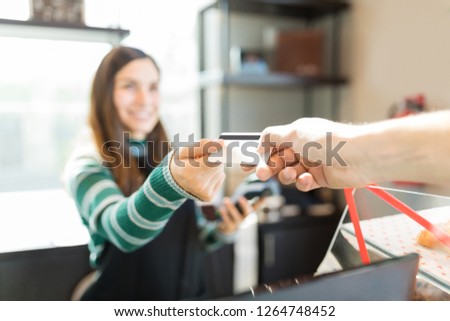 Cropped image of customer giving credit card to cashier in bakery