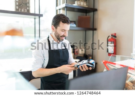 Confident baker inserting credit card in POS terminal at shop