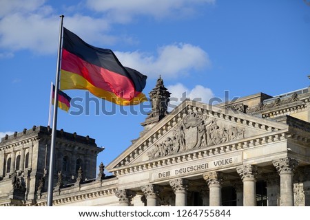 facade of the german parliament in berlin with a sign "Dem Deutschen Volke" and the german Flac in front Royalty-Free Stock Photo #1264755844