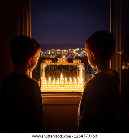 Two boys looking at the Menorah on the eighth night of Hanukkah