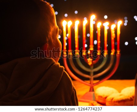 A child looking at Hanukkah candles. It is a Jewish custom to light candles on the 8 days of Hanukkah celebrating the miraculous victory over the ancient Greeks during the Second Temple period.